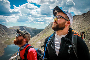 Two men in hiking gear with mountains in background